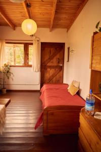 a bedroom with a bed with a red blanket and a door at Cabaña Viedma in Viedma