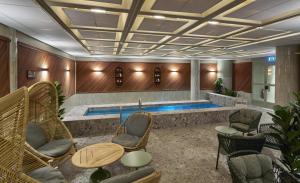 a swimming pool in a room with chairs and tables at Scandic Skellefteå in Skellefteå