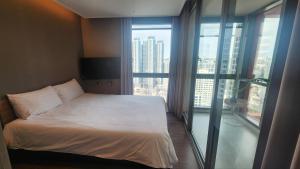 a bedroom with a bed and a large window at Haeon stay haeundae in Ch'ŏngsap'o