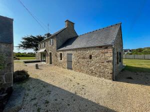 an old stone building with a garage in a field at AR PENNITI - Magnifique maison en pierre proche plage in Landéda