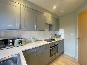 a kitchen with gray cabinets and a sink and a microwave at Catbells in Keswick +18 photos
