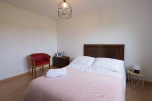 a bedroom with a white bed and a red chair at TY BIHAN - Charmante maison de plein-pied proche mer in Ploudalmézeau