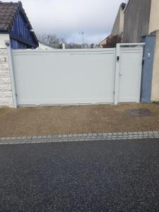 a white fence with two doors in a yard at Appartement Duplex 40 M² in Fontenay-Trésigny