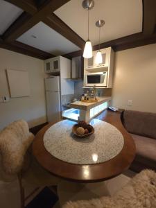 a kitchen and living room with a table and a couch at Flat Luxo 3010 com banheira Mountain Village Laje de Pedra Canela in Canela