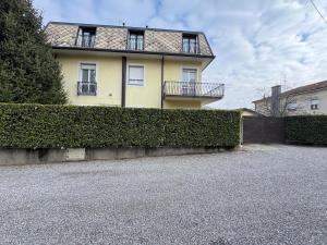 a yellow house with a hedge in front of it at Appartamento Belvedere in Lomazzo
