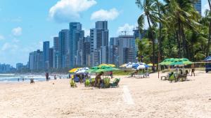 a beach with people sitting in chairs and umbrellas at Flat in Boa Viagem leisure great location PM805 in Recife