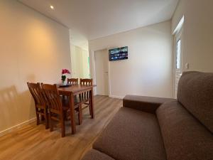 a living room with a table and chairs and a couch at Casa das Orquídeas Meco in Sesimbra