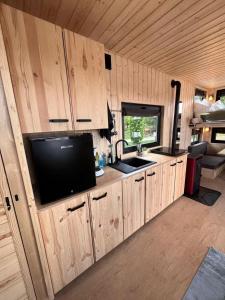 a kitchen with wooden cabinets and a flat screen tv at Berlin River Retreat in Berlin