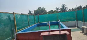 a swimming pool with a green fence and a swimming pool at Elite Castle Stay in Kottakupam