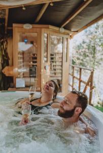 a man and a woman sitting in a bathtub with a glass of wine at Domaine Kaet in Ratenelle