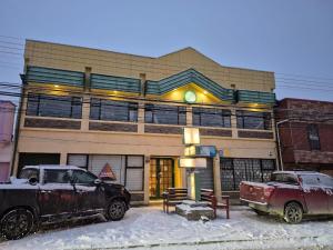a truck parked in front of a building in the snow at Hostal Don Guillermo in Puerto Natales
