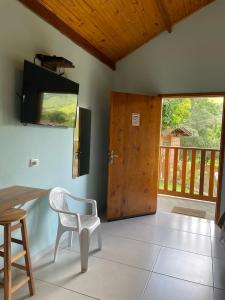 a room with a table and a chair and a door at Chales Sao Felix in São Bento do Sapucaí