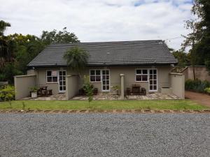 a small white house on a gravel road at Fern Rivers Self-Catering Accommodation in Pietermaritzburg