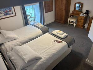 a bedroom with two beds with towels on them at The Swordfish Inn in Penzance