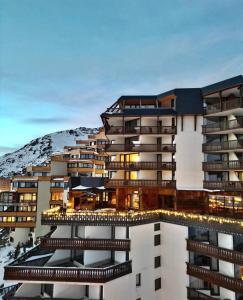 a building with a mountain in the background at Hotel Le Portillo in Val Thorens