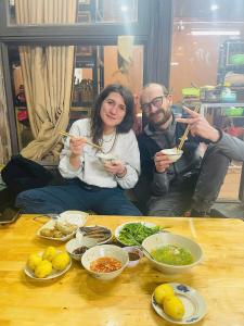 a man and woman sitting at a table eating food with chopsticks at Cloud Garden in Bắc Yên
