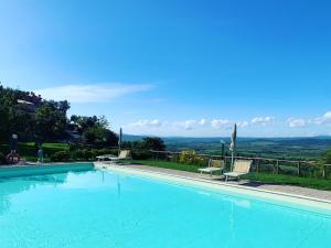 a large swimming pool with two chairs and a view at La Cianella - Adult Only in Scarlino