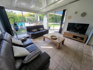 a living room with a leather couch and a tv at Bas de villa moderne avec piscine in Fréjus