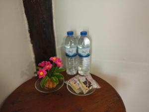 two bottles of water and flowers on a wooden table at Koh jum Mutu Home Stay in Ban Ko Phrao