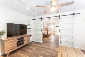 a living room with a flat screen tv and a ceiling fan at Beachside Bungalow steps from sand in San Diego