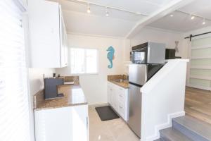a kitchen with white cabinets and a refrigerator at Beachside Bungalow steps from sand in San Diego
