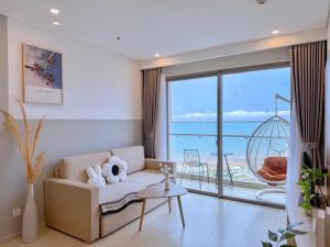 a living room with a couch and a view of the ocean at The Sóng Vung Tau Apartment - Pool Near Sea in Vung Tau