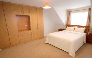 a bedroom with a white bed and a large cabinet at Large 3 bed Duplex Apartment - Rhebogue Limerick in Limerick