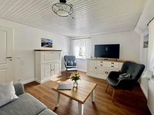 a living room with a couch and chairs and a tv at Haus Petje in Keitum
