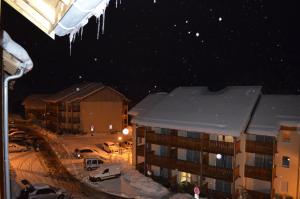 a building with snow on the roof at night at Les Reflets d'Ax in Ax-les-Thermes