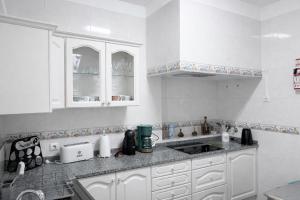 a kitchen with white cabinets and a sink at Violeta House in Funchal +11 photos