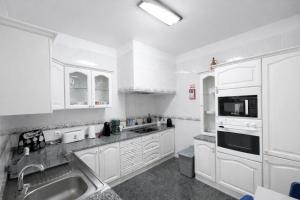a kitchen with white cabinets and a sink at Violeta House in Funchal