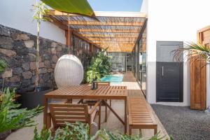 an outdoor patio with a wooden table and chairs at BaliHouse by Aura Collection in La Oliva