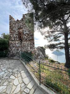 an old stone building with a tree and a fence at Bergeggi Sea View Apartment - Torre del Mare in Bergeggi