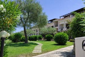 a garden in front of a building with a tree at Blue Bay Apartment in Cala Bitta