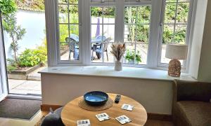 a living room with a table in front of windows at 14 Granite Henge in Looe