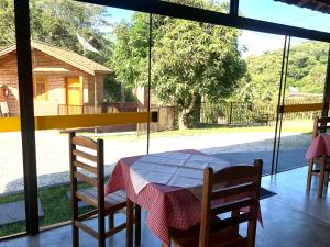 a table and chairs in a room with a window at Chales Sao Felix in São Bento do Sapucaí
