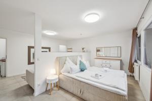 a bedroom with a bed with white sheets and a table at Ramoni Apartments - Bergzauber Kniebis in Freudenstadt