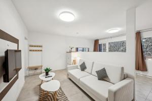 a living room with a white couch and a tv at Ramoni Apartments - Bergzauber Kniebis in Freudenstadt