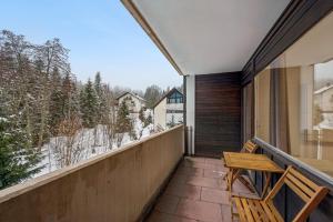 a balcony with a wooden bench and a view of the snow at Ramoni Apartments - Bergzauber Kniebis in Freudenstadt
