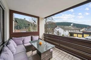 a balcony with a couch and a glass table at Ramoni Apartments - Lichtblick in Enzklösterle