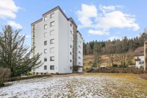 a white building on a snowy field with trees at Ramoni Apartments - Lichtblick in Enzklösterle