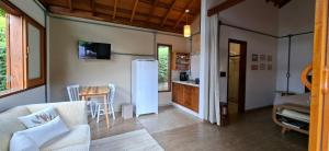 a living room with a couch and a refrigerator at Chalé das Flores - Refúgio com clima de chácara no Centro de Gonçalves in Gonçalves +5 photos