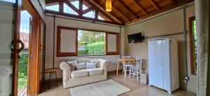 a living room with a couch and a refrigerator at Chalé das Flores - Refúgio com clima de chácara no Centro de Gonçalves in Gonçalves