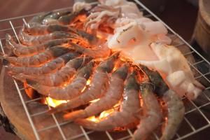 a bunch of food cooking on a grill at Kirati Beach Resort in Choeng Mon Beach