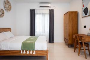 a bedroom with a bed and a desk and a window at The Aura Inn in Kerobokan +29 photos