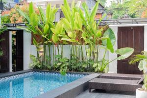 a swimming pool in a garden with plants at The Aura Inn in Kerobokan