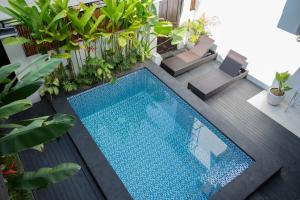 a swimming pool in the middle of a patio with plants at The Aura Inn in Kerobokan