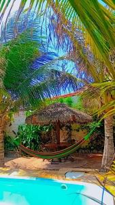 a hammock and umbrella on a beach with palm trees at BELL MAR CHALéS 01e 02 in Luis Correia