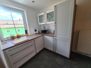 a kitchen with white cabinets and a large window at Apartment Waldstein Terrassen by Interhome in Weißenstadt