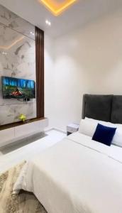 a bedroom with a white bed and a tv on the wall at 5bedroom duplex self compound in Lekki